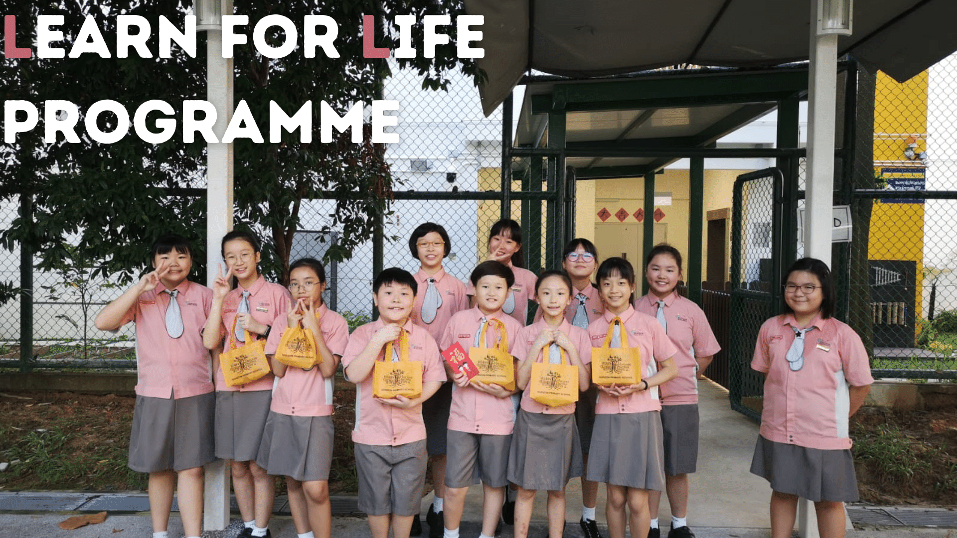 Group of students in pink uniforms holding yellow bags outdoors, with text reading Learn For Life Programme.